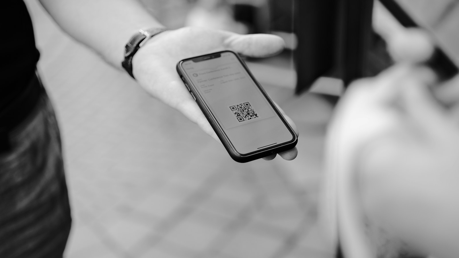 Dłoń trzymająca telefon z kodem QR na ekranie