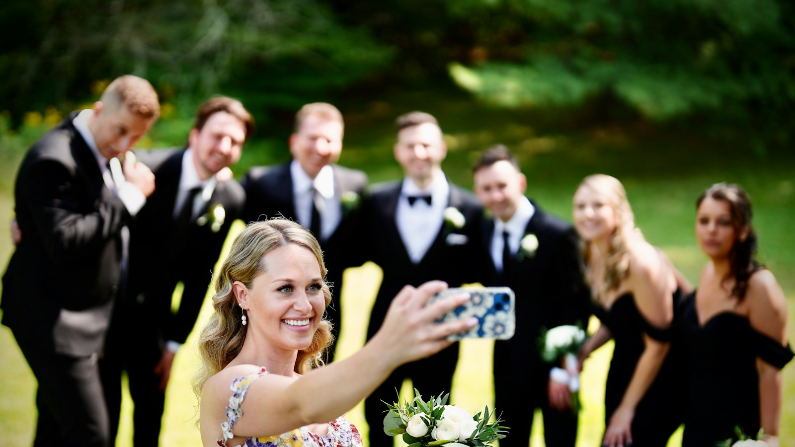 Panna młoda robi selfie z drużbami i druhnami w ogrodzie