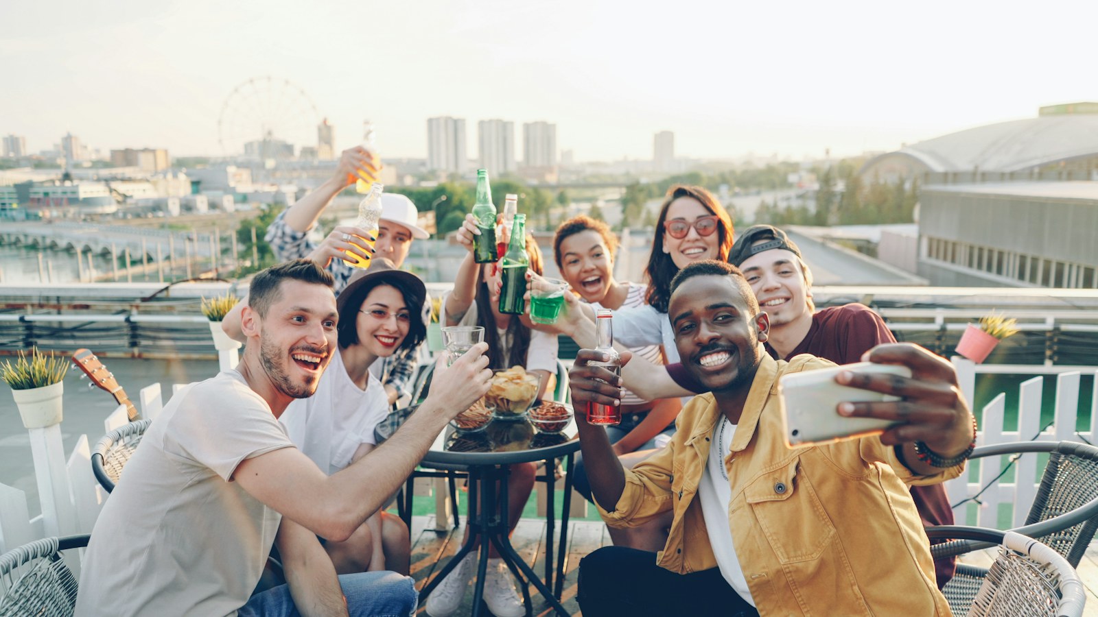 Znajomi robią wspólne selfie przy stoliku na dachu, w tle miasto